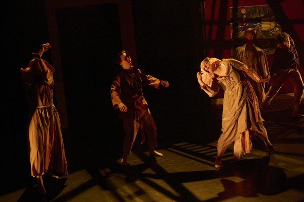 A group of young men and women dance in old-fashioned beige clothing.